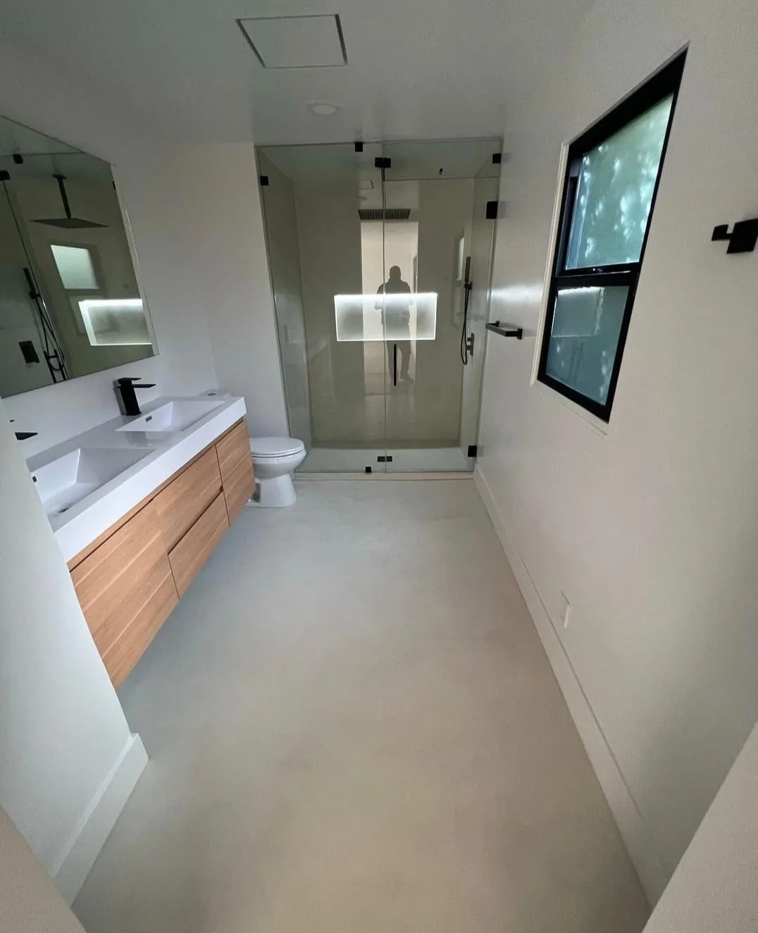 Modern bathroom renovation with wood vanity, walk-in shower, and black-framed window