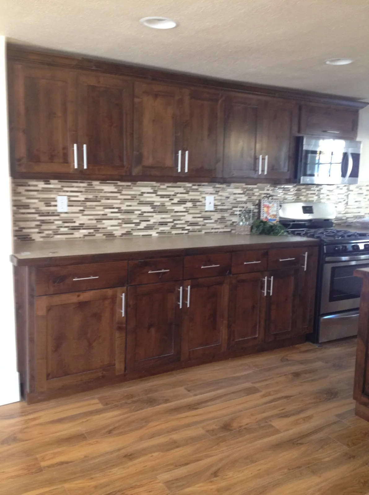 Kitchen remodel with wood cabinets, mosaic backsplash, and stone countertop