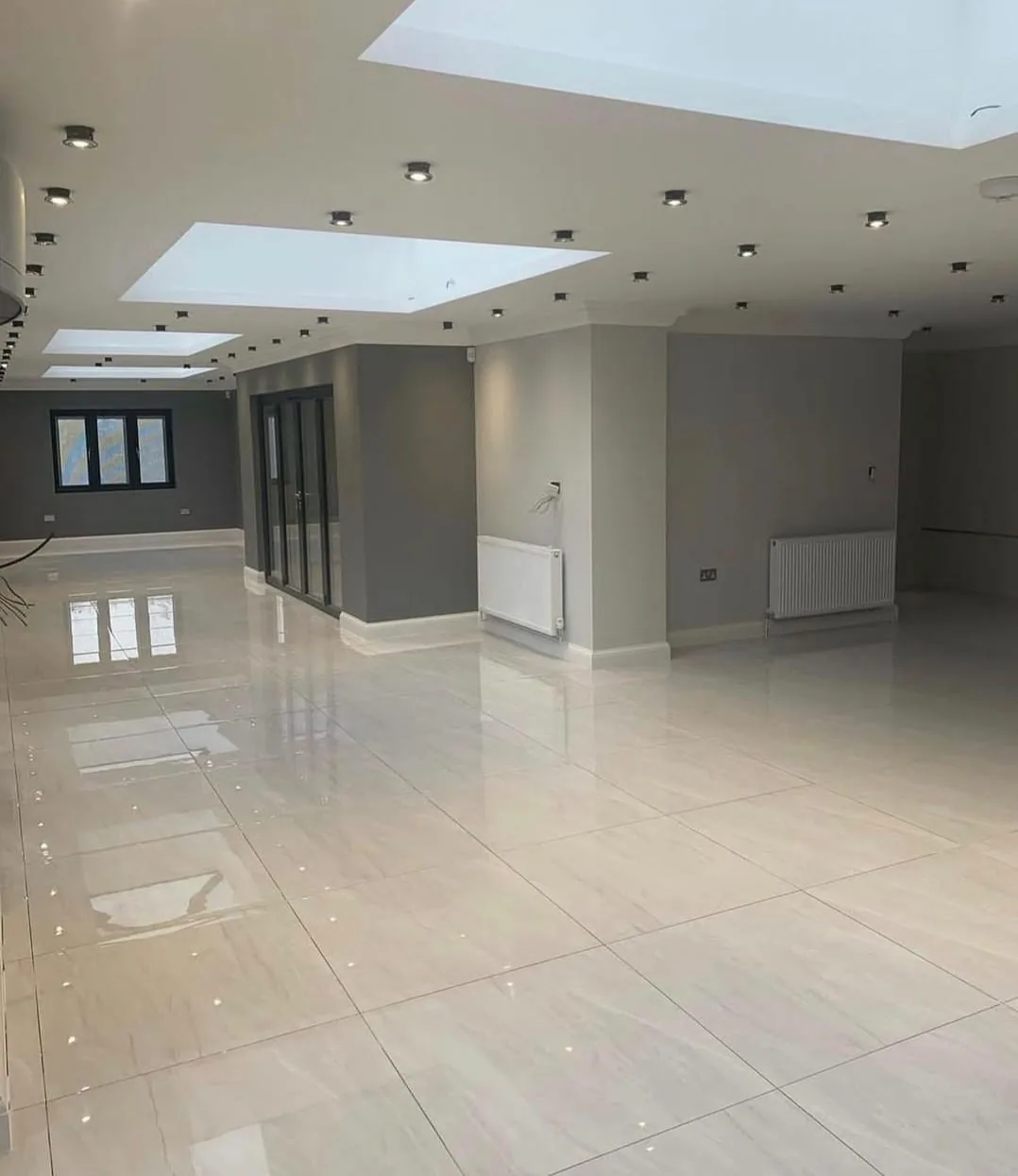 Large renovated room with polished tile floors and skylights